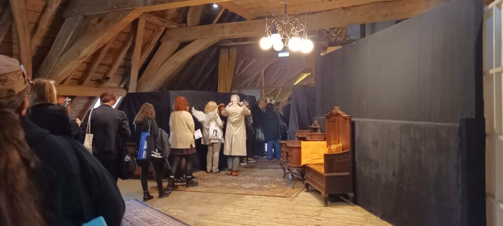 People in a queue underneath some beautiful attic beams and a chandelier. 